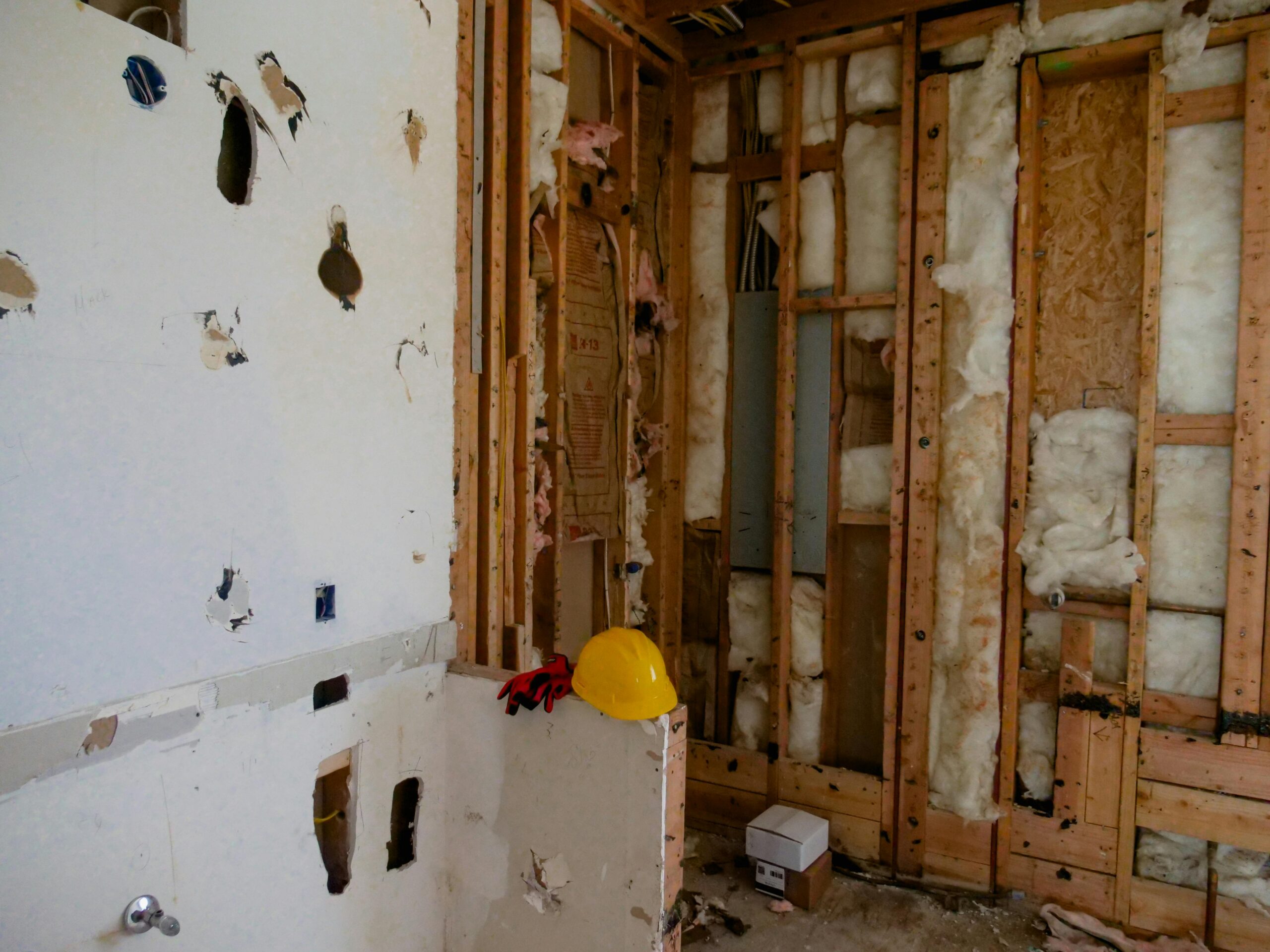 image of damaged walls on a home's interior with insulation spread out unevenly throughout the image.