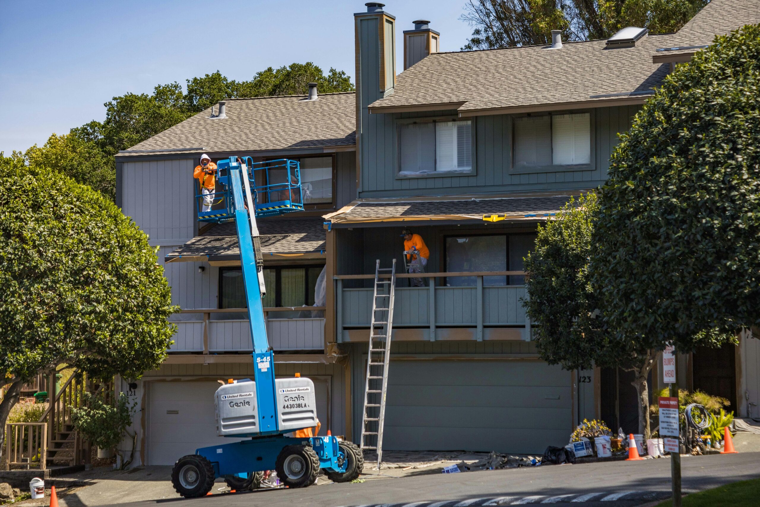 two construction workers with heavy machinery repairing the exterior of a home